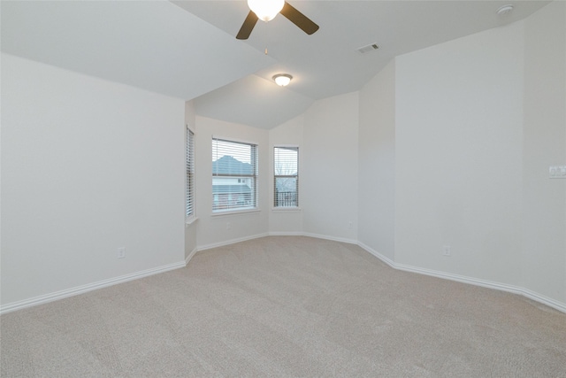 empty room with visible vents, baseboards, ceiling fan, vaulted ceiling, and light colored carpet