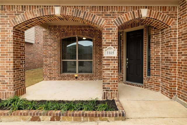 doorway to property featuring brick siding