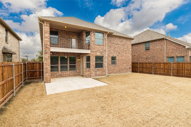 back of property with a balcony, a patio area, brick siding, and a fenced backyard