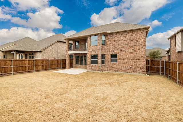 back of property with a patio, a fenced backyard, roof with shingles, a balcony, and brick siding