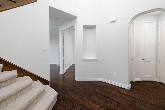 stairway featuring hardwood / wood-style floors, baseboards, and arched walkways