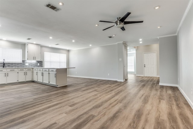 kitchen with visible vents, white cabinetry, crown molding, and open floor plan