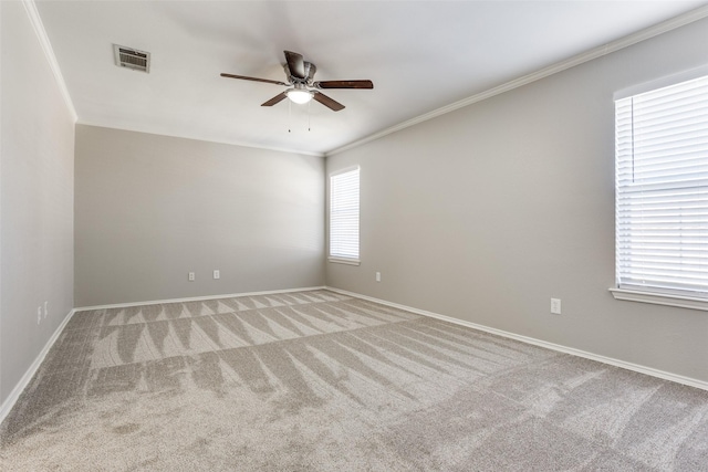 unfurnished room with visible vents, crown molding, baseboards, light colored carpet, and ceiling fan