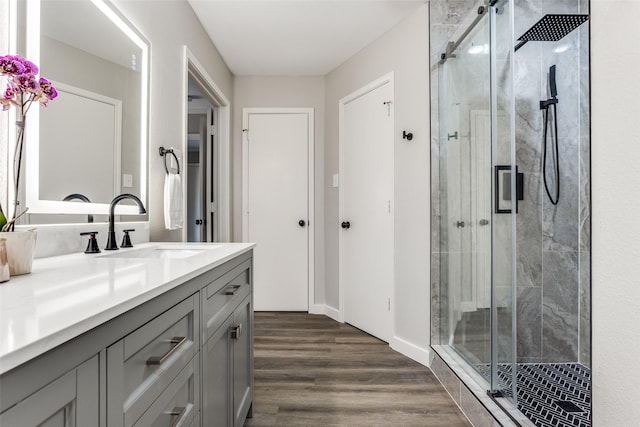 bathroom featuring baseboards, vanity, wood finished floors, and a shower stall