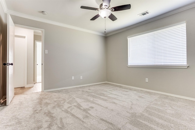 spare room featuring carpet, baseboards, visible vents, ceiling fan, and ornamental molding