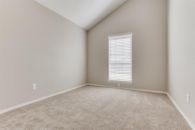 carpeted spare room with vaulted ceiling