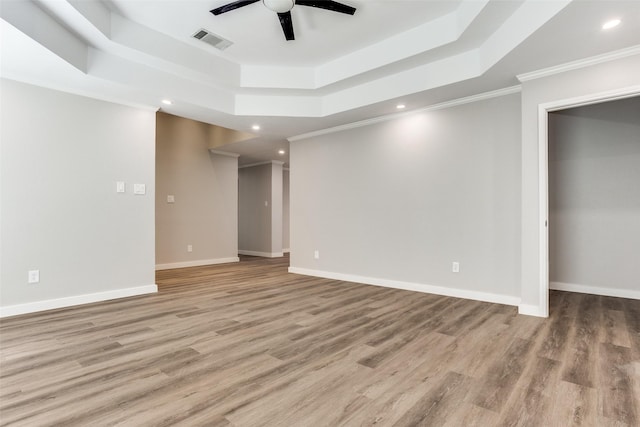 spare room with a raised ceiling, wood finished floors, visible vents, and baseboards