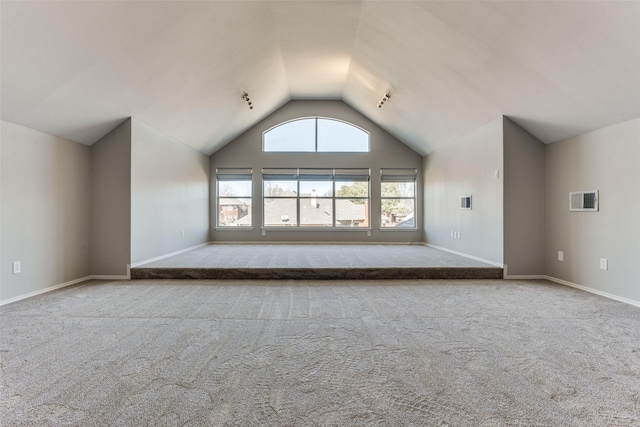 empty room with vaulted ceiling, carpet, visible vents, and baseboards