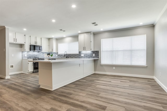 kitchen featuring a peninsula, stainless steel appliances, light countertops, and wood finished floors