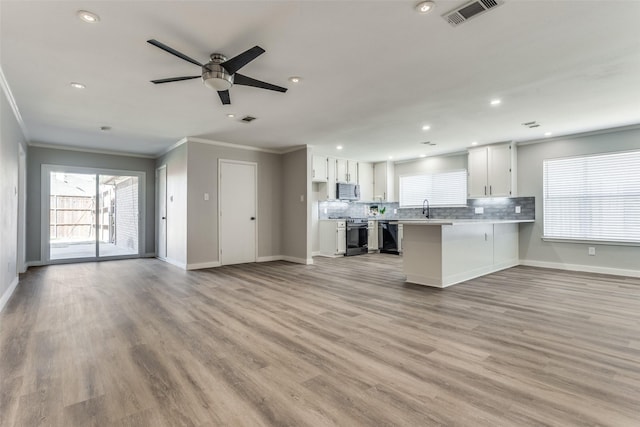 kitchen with tasteful backsplash, visible vents, open floor plan, appliances with stainless steel finishes, and a peninsula