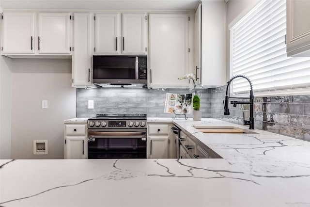 kitchen featuring white cabinets, light stone countertops, appliances with stainless steel finishes, and a sink