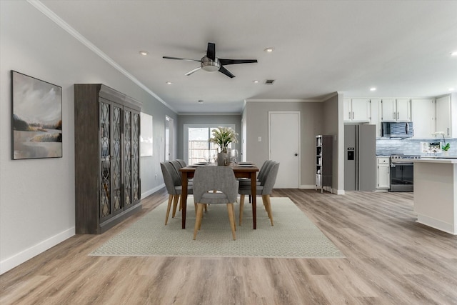 dining area with baseboards, crown molding, and light wood finished floors