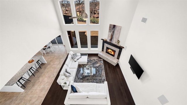 living room with visible vents, a lit fireplace, and a high ceiling