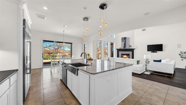 kitchen featuring light tile patterned floors, a sink, visible vents, and white cabinets