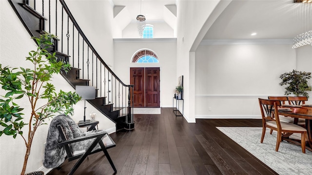 foyer entrance with a high ceiling, baseboards, ornamental molding, stairway, and dark wood finished floors