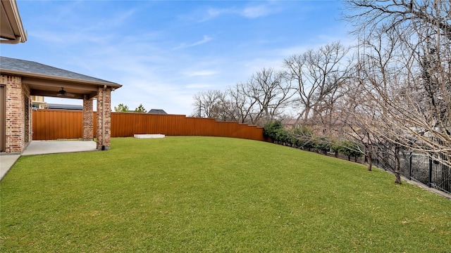 view of yard featuring a fenced backyard, a ceiling fan, and a patio