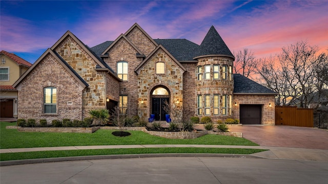 french country home featuring a yard, brick siding, driveway, and an attached garage