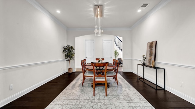 dining space featuring dark wood-style floors, arched walkways, visible vents, and ornamental molding