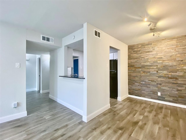 spare room featuring baseboards, visible vents, and wood finished floors