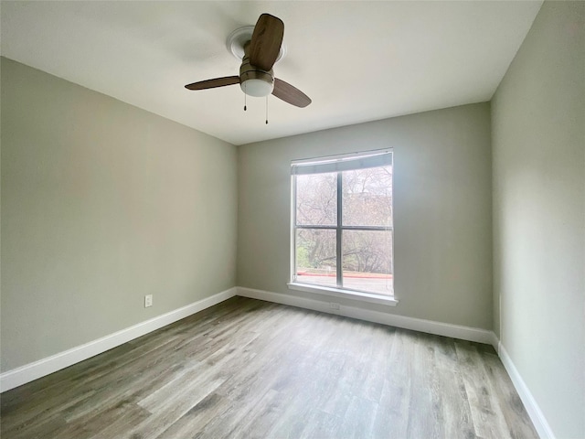 empty room with a ceiling fan, baseboards, and wood finished floors