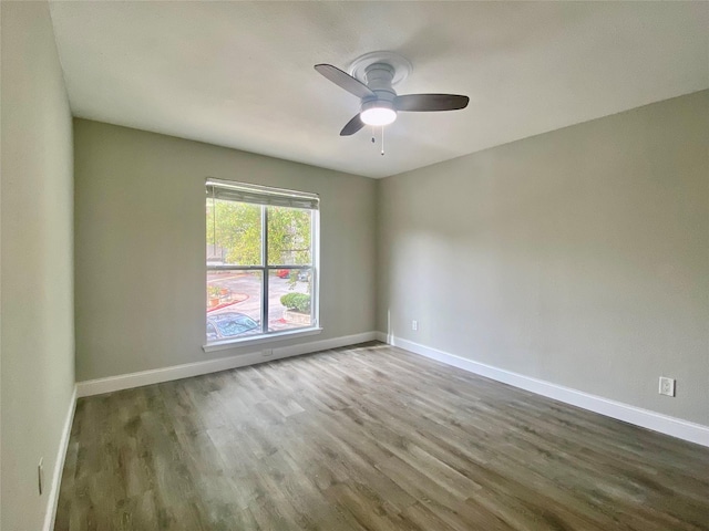 empty room featuring ceiling fan, baseboards, and wood finished floors