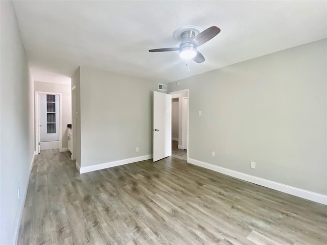 empty room featuring visible vents, wood finished floors, a ceiling fan, and baseboards