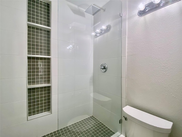 full bath with a textured wall, a tile shower, and toilet