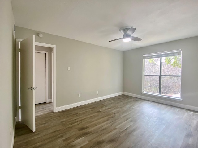 empty room with a ceiling fan, baseboards, and dark wood-style flooring