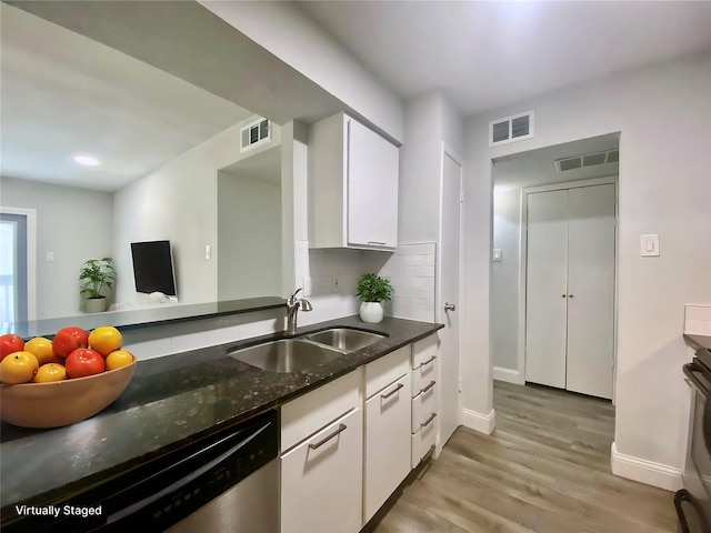 kitchen featuring stainless steel dishwasher, a sink, visible vents, and tasteful backsplash