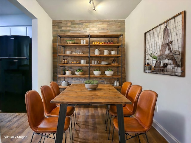 dining space with an accent wall, baseboards, and wood finished floors