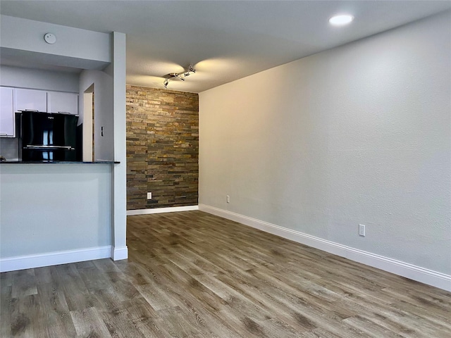 unfurnished living room with rail lighting, baseboards, and wood finished floors