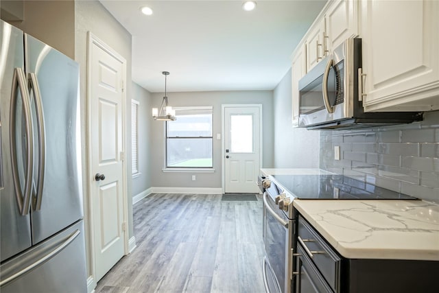 kitchen with stainless steel appliances, light wood-style flooring, decorative backsplash, white cabinetry, and baseboards