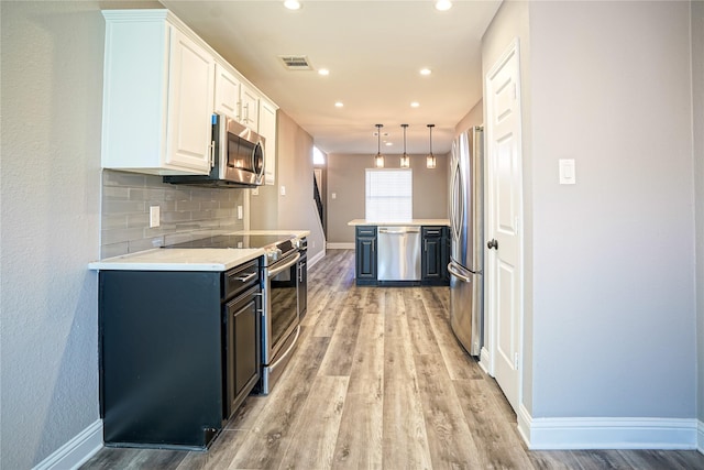 kitchen with tasteful backsplash, light countertops, light wood-style flooring, appliances with stainless steel finishes, and white cabinetry