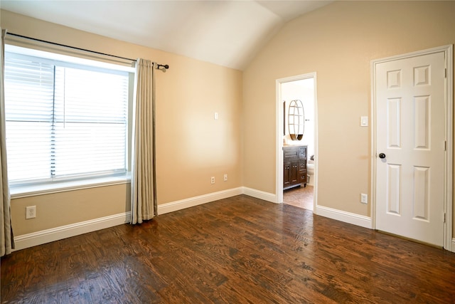 unfurnished room featuring dark wood-type flooring, vaulted ceiling, and baseboards