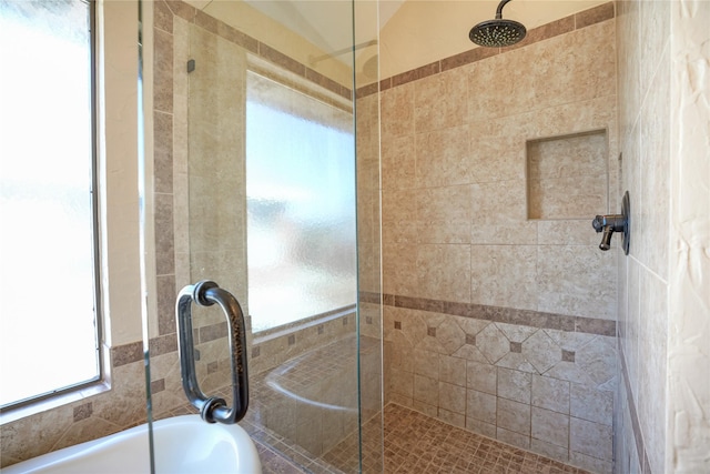 bathroom with a tub to relax in and tiled shower