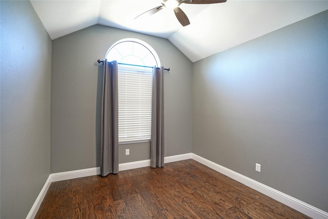 empty room featuring dark wood-type flooring, vaulted ceiling, baseboards, and a ceiling fan