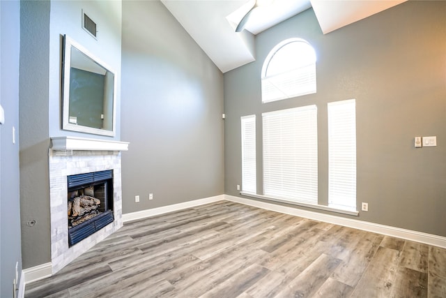 unfurnished living room featuring high vaulted ceiling, a fireplace, wood finished floors, visible vents, and baseboards