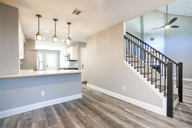 kitchen with baseboards, wood finished floors, visible vents, and white cabinets