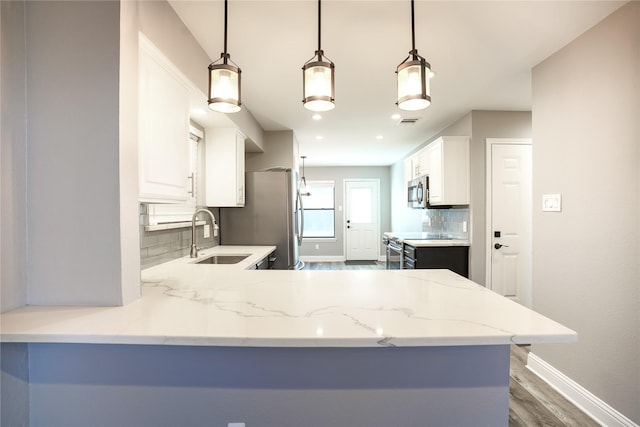 kitchen featuring stainless steel appliances, tasteful backsplash, white cabinetry, a sink, and light stone countertops