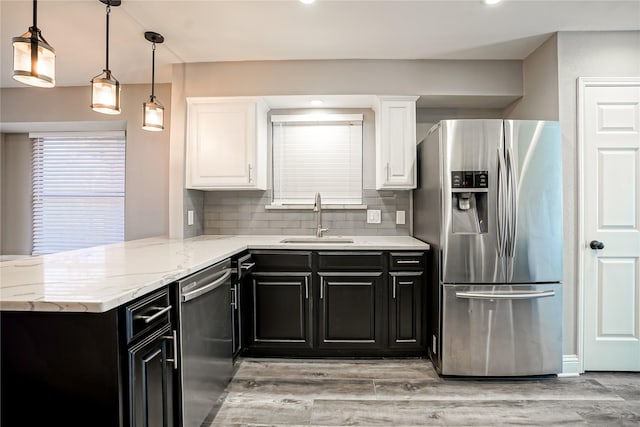 kitchen with dark cabinetry, appliances with stainless steel finishes, white cabinets, and a sink