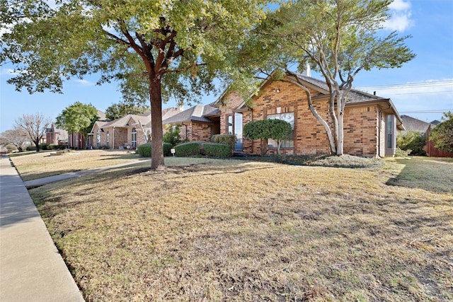 ranch-style home with a front yard and brick siding