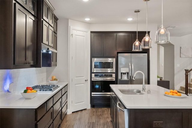 kitchen featuring under cabinet range hood, a sink, dark brown cabinets, appliances with stainless steel finishes, and light countertops