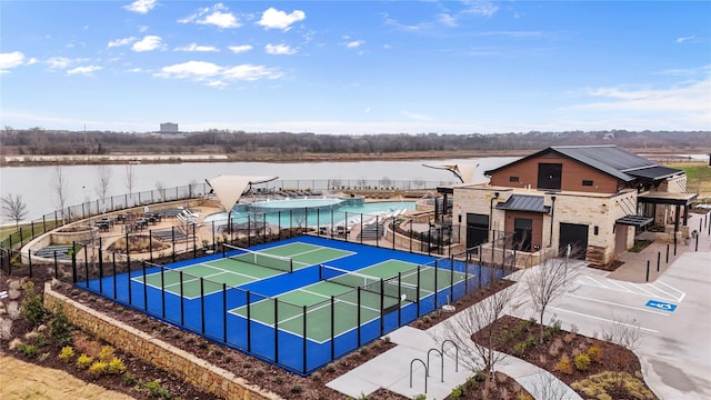 view of tennis court with a water view and fence