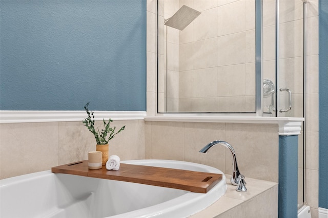 full bath featuring a textured wall, a shower stall, and a bath