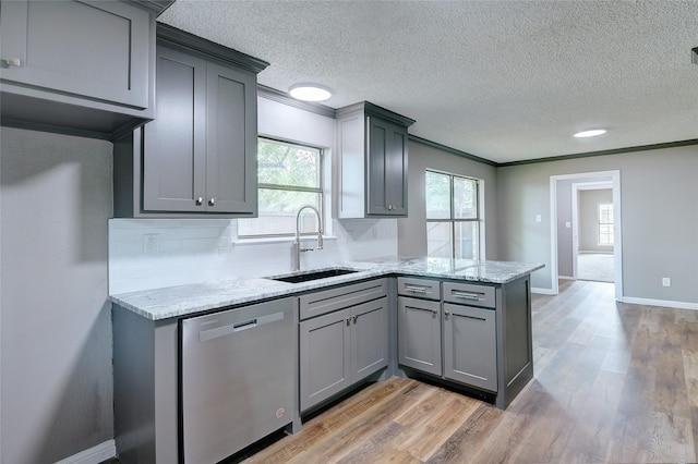 kitchen with light wood-style flooring, a peninsula, a sink, stainless steel dishwasher, and gray cabinets