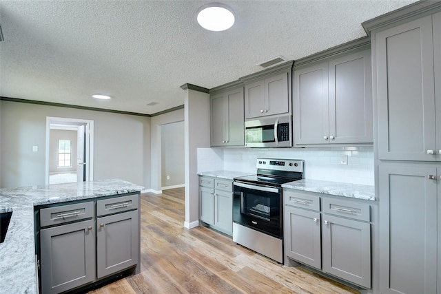 kitchen featuring light wood-style floors, appliances with stainless steel finishes, and gray cabinetry