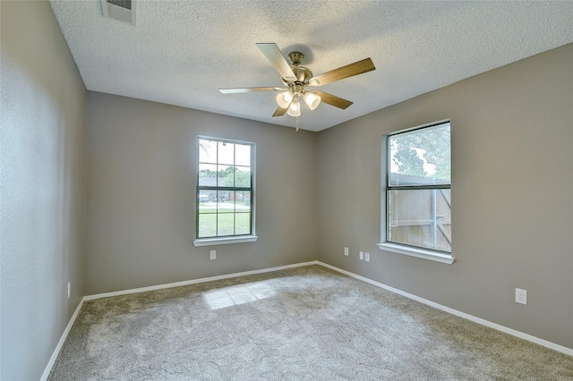 carpeted empty room with ceiling fan, a textured ceiling, visible vents, and baseboards