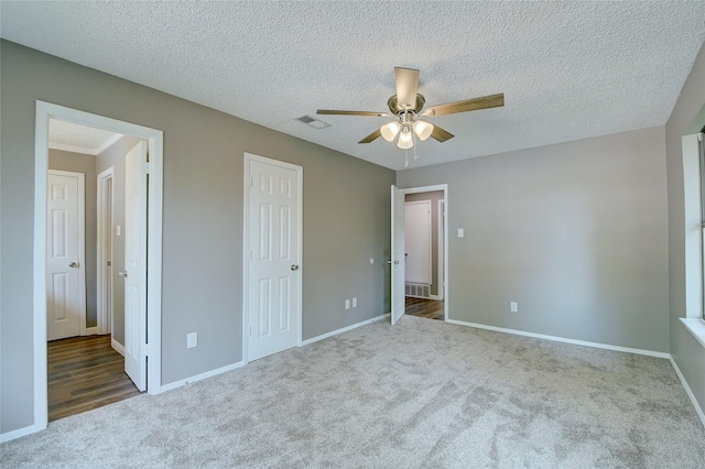 unfurnished bedroom with carpet floors, visible vents, a textured ceiling, and baseboards