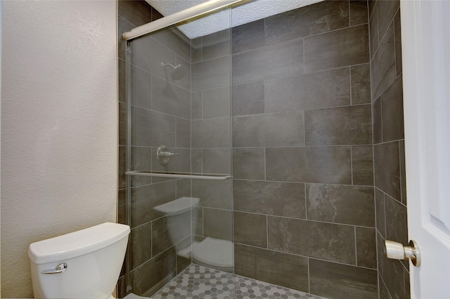 bathroom featuring a textured wall, a shower stall, and toilet