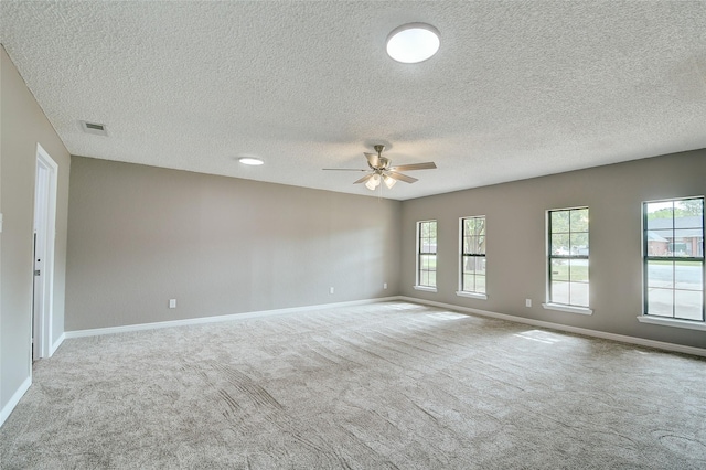 carpeted spare room with ceiling fan, visible vents, and baseboards